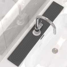 a bathroom sink with a black mat on the floor next to it and a faucet