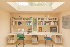 a room with a skylight and some bookshelves on the wall next to two chairs