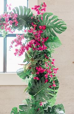 a plant with pink flowers and green leaves on it in front of a window sill