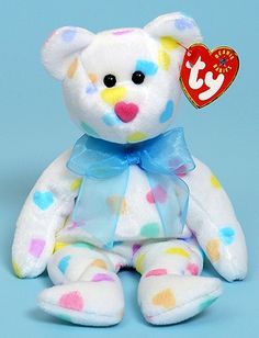 a white teddy bear with multicolored spots on it's body and a blue ribbon around its neck