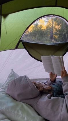 a person laying in a tent reading a book