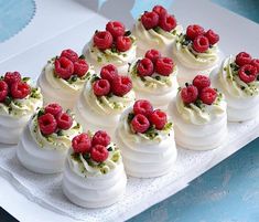 there are many small desserts with raspberries on top of each one in the box