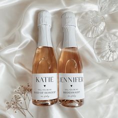 two bottles of wine sitting next to each other on a white satin covered tablecloth