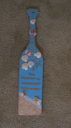 a bottle shaped sign with shells on it