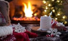 a coffee cup sitting on top of a table next to a fire place with christmas decorations