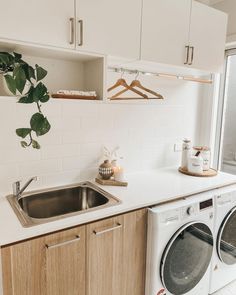 a washer and dryer sitting in a kitchen next to a window with plants on it