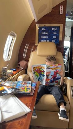 a young boy sitting in an airplane reading a comic book