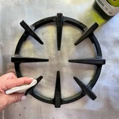 a person is using a bottle opener to make a circular design on a metal surface