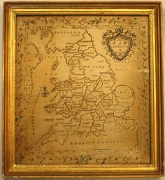 an old map hanging on the wall in front of a wooden frame with gold trim