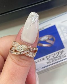 a woman's hand holding a ring with two diamonds on it and an id card in the background