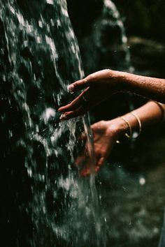 a woman's hand reaching into a water fountain