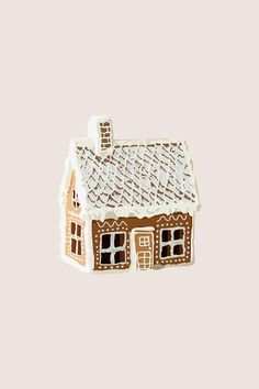 a brown and white gingerbread house brooch with windows on the roof is shown in front of a light gray background