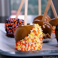 chocolate covered apples with sprinkles and wooden sticks on a silver platter