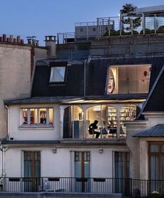 two people are standing on the balcony of a building at night with their windows open