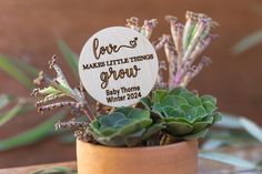 a wooden sign that says love makes little things grow on top of a potted plant