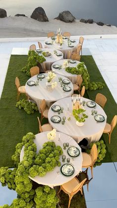 an outdoor dining area with tables and chairs covered in green grass next to the water