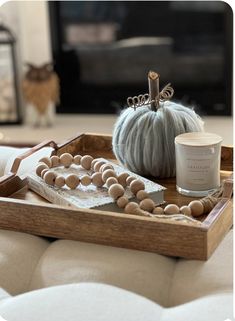 a wooden tray with beads, candles and a candle holder on it in front of a fireplace