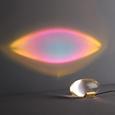 a lamp that is sitting on the floor in front of a wall with a rainbow colored light coming out of it