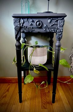 a small table with a potted plant in it on top of a wooden floor