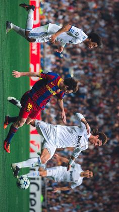 three men are playing soccer against each other on the field in front of an audience