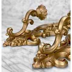 an ornately decorated gold metal object on a marble surface with white and gray background