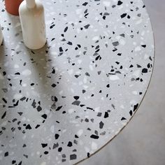 two white vases sitting on top of a marbled table with black and white speckles