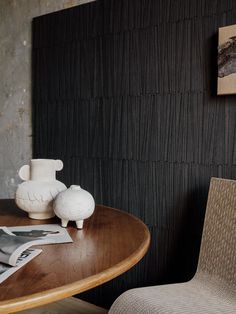 a wooden table with two white vases on top of it next to a chair