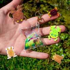 a person's hand holding several different shaped keychains in front of them