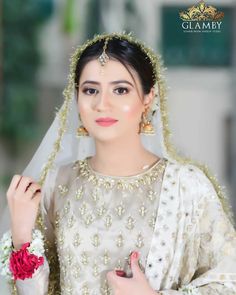 a woman wearing a white and gold bridal outfit with flowers in her hair is posing for the camera