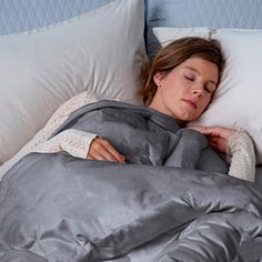 a woman laying in bed with her eyes closed and she is covered by a blanket