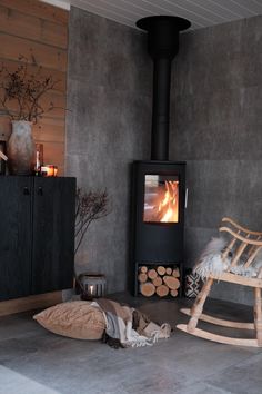 a rocking chair sitting in front of a fire place next to a pile of logs