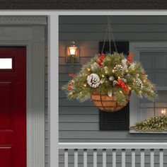 a hanging basket filled with christmas decorations in front of a red door on a house