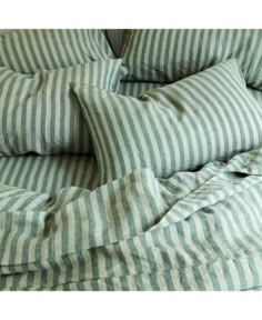 an unmade bed with green and white striped sheets