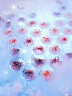 many small cups filled with food on top of a white tablecloth covered in bubbles