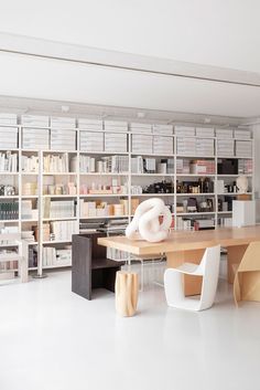 a room filled with lots of bookshelves next to a wooden table and chairs