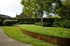 a lush green yard surrounded by trees and bushes with a brick path leading to it