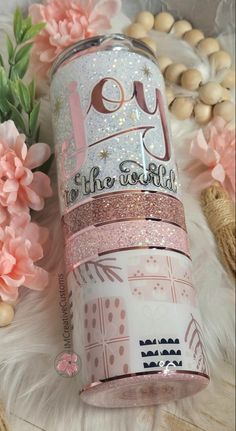 the pink glitter tumbler is next to some flowers and beads on a white furnishing