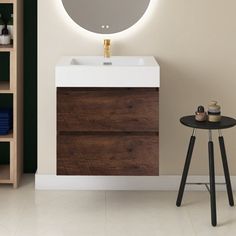 a white sink sitting under a round mirror next to a wooden table with a stool