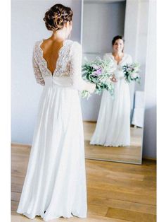 a woman standing in front of a mirror wearing a white dress and holding a bouquet