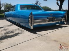 an old blue car is parked in the driveway