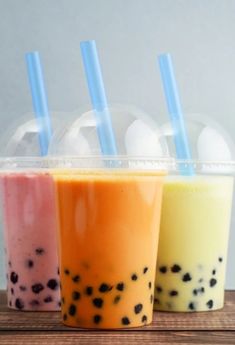 three drinks in plastic cups with straws on the top and one is filled with bubble tea