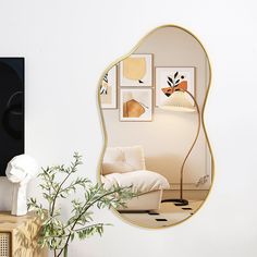 a mirror that is on the wall next to a vase with a plant in it