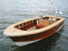 a small wooden boat floating on top of the water with a flag in it's bow