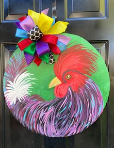 a door hanger with a rooster painted on it's side and a flower in the center