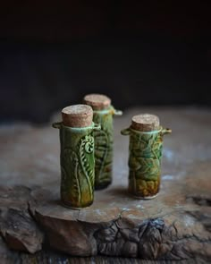 three green vases sitting on top of a rock