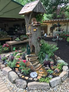 a small tree house in the middle of a garden with lots of plants and rocks