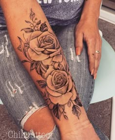 a woman's arm with roses and leaves tattooed on the side of her leg