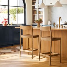 two wooden chairs sitting in front of a kitchen island