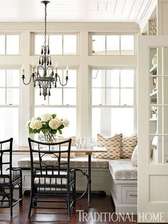 a dining room table and chairs with chandelier in the center, next to a window