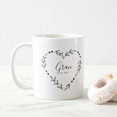 a white coffee mug sitting next to a donut